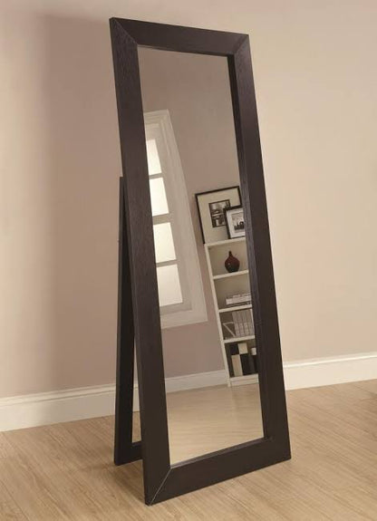 Black floor mirror leaning against a wall in a room with a bookshelf.
