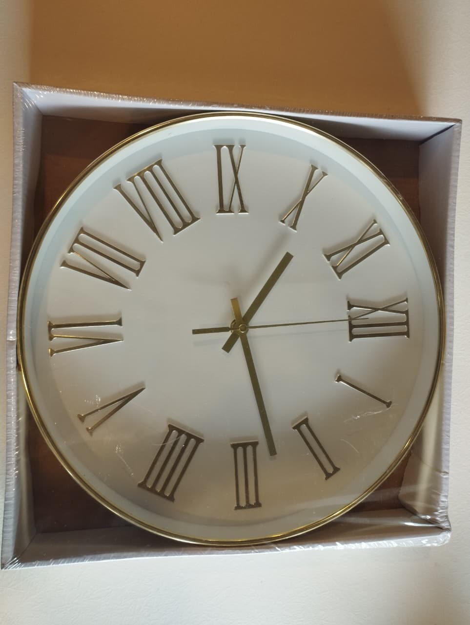 Round clock with gold rim and Roman numerals